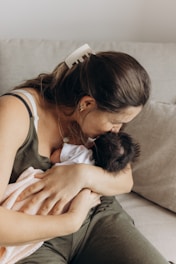 a woman sitting on a couch holding a baby