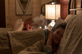 Woman relaxing in bed under a heated plaid, blue glacier light subtly glowing, creating a cozy atmosphere.