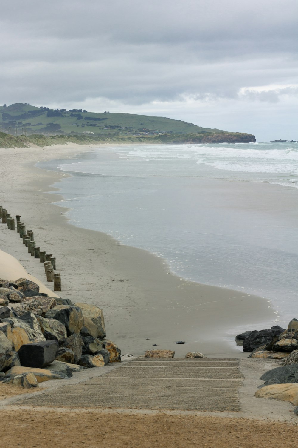 a sandy beach with steps leading to the water