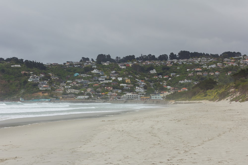 une plage de sable avec des maisons sur une colline en arrière-plan