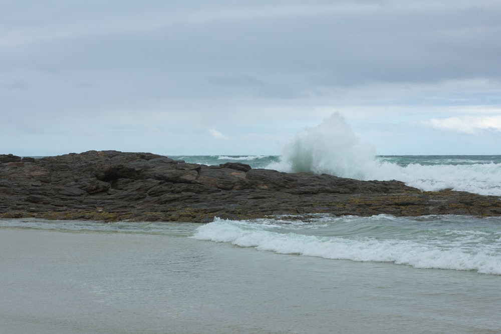 a wave crashing on a rocky shore on a cloudy day