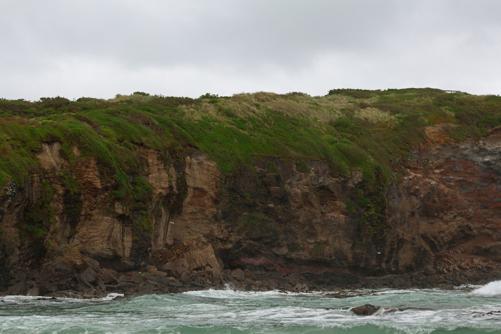 a rocky cliff with a body of water in front of it