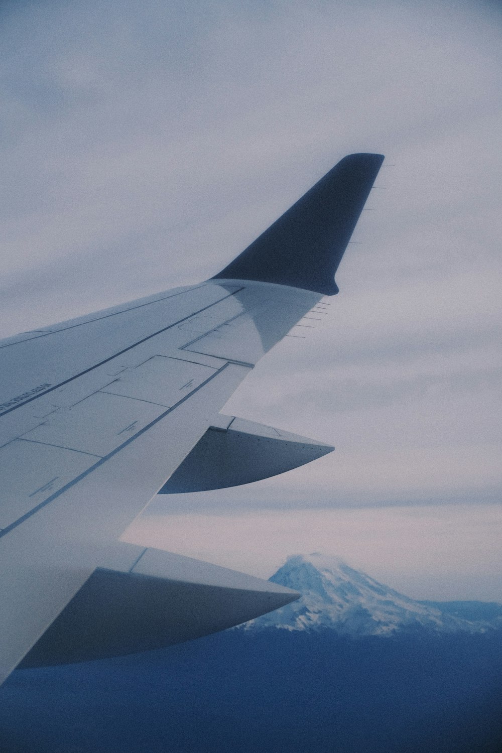 a view of the wing of an airplane with a mountain in the background