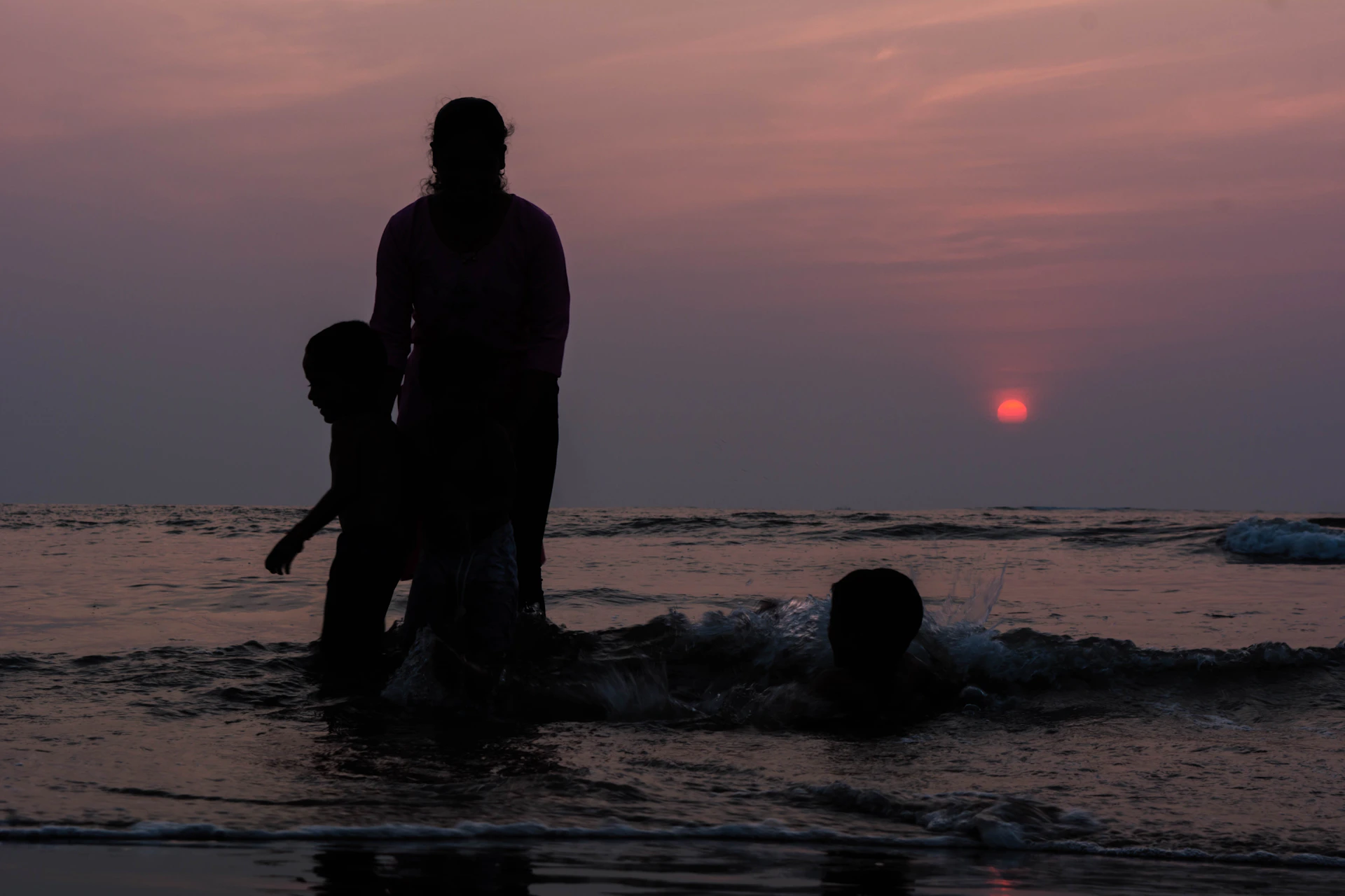 Sunset over the ocean with silhouettes of whales spouting water, creating a magical end to a whale watching day in Samana.