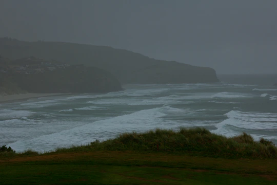 A moody coastal landscape with fog rolling over the sea at dawn.