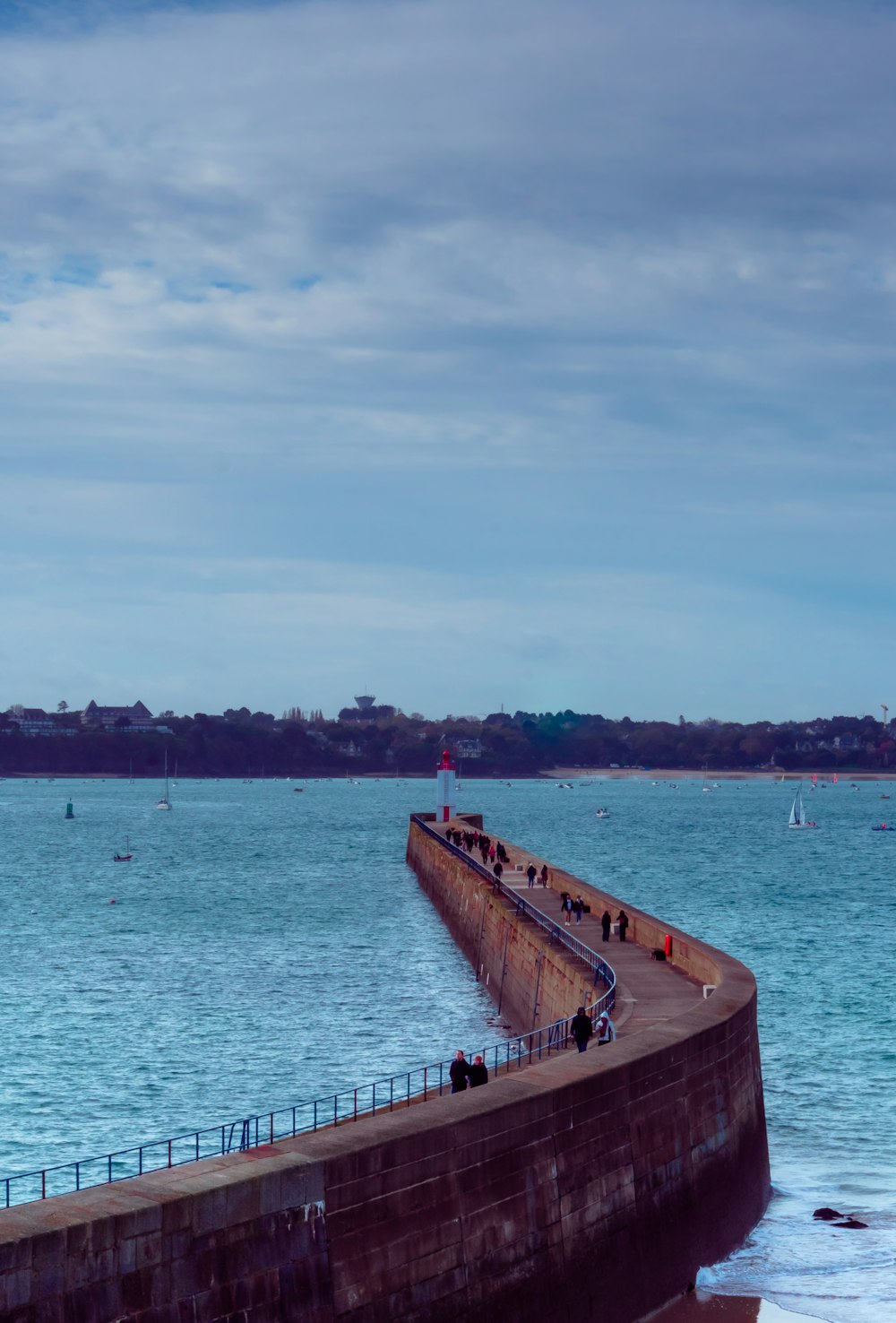 a group of people standing on a pier next to the ocean