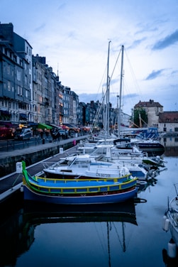 A serene view of Naoussa harbor at sunset with whitewashed buildings and boats gently bobbing in the water.