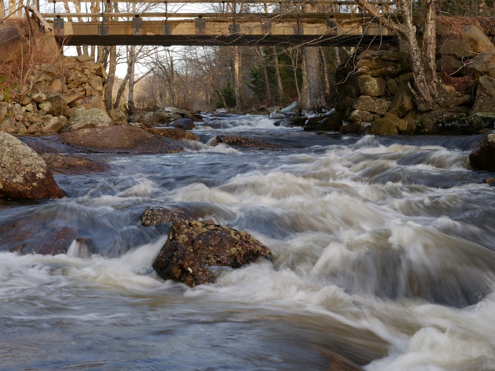 a bridge over a river with rapids and rocks