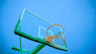A sturdy basketball hoop mounted on a driveway with a clear blue sky overhead.