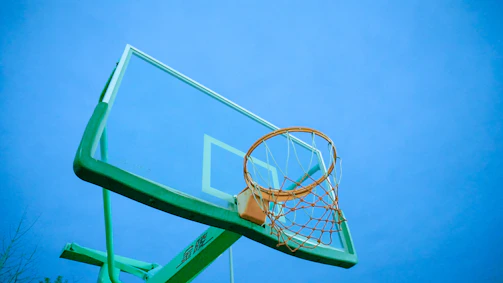 A sturdy basketball hoop mounted on a driveway with a clear blue sky overhead.