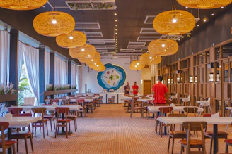 Warmly lit dining area with elegant wooden tables and vibrant Indian artwork on the walls.