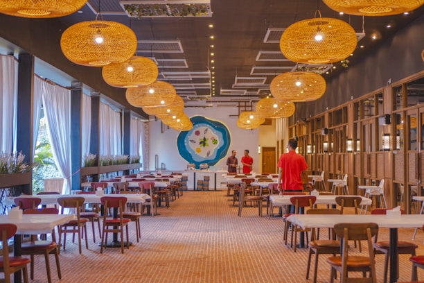 Warmly lit dining area with maroon and gold accents, tables set for family meals.