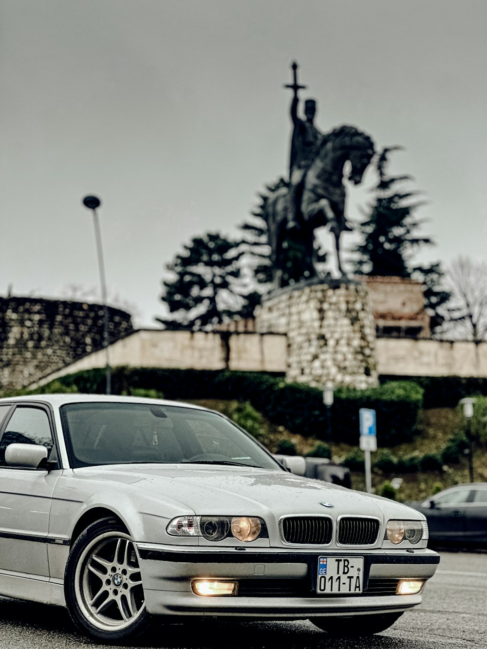 a white car parked in front of a statue