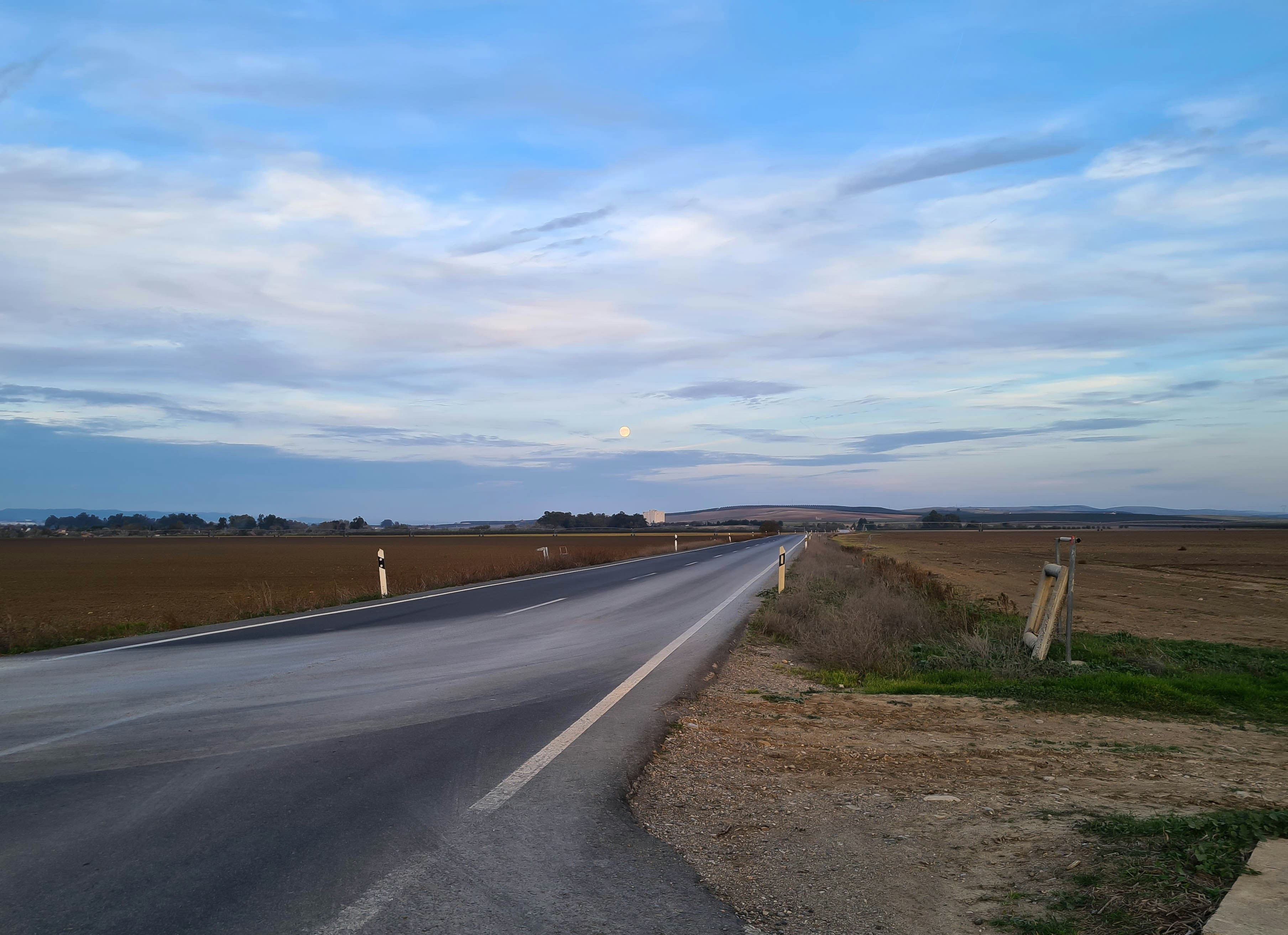 uma longa estrada vazia com um céu azul ao fundo