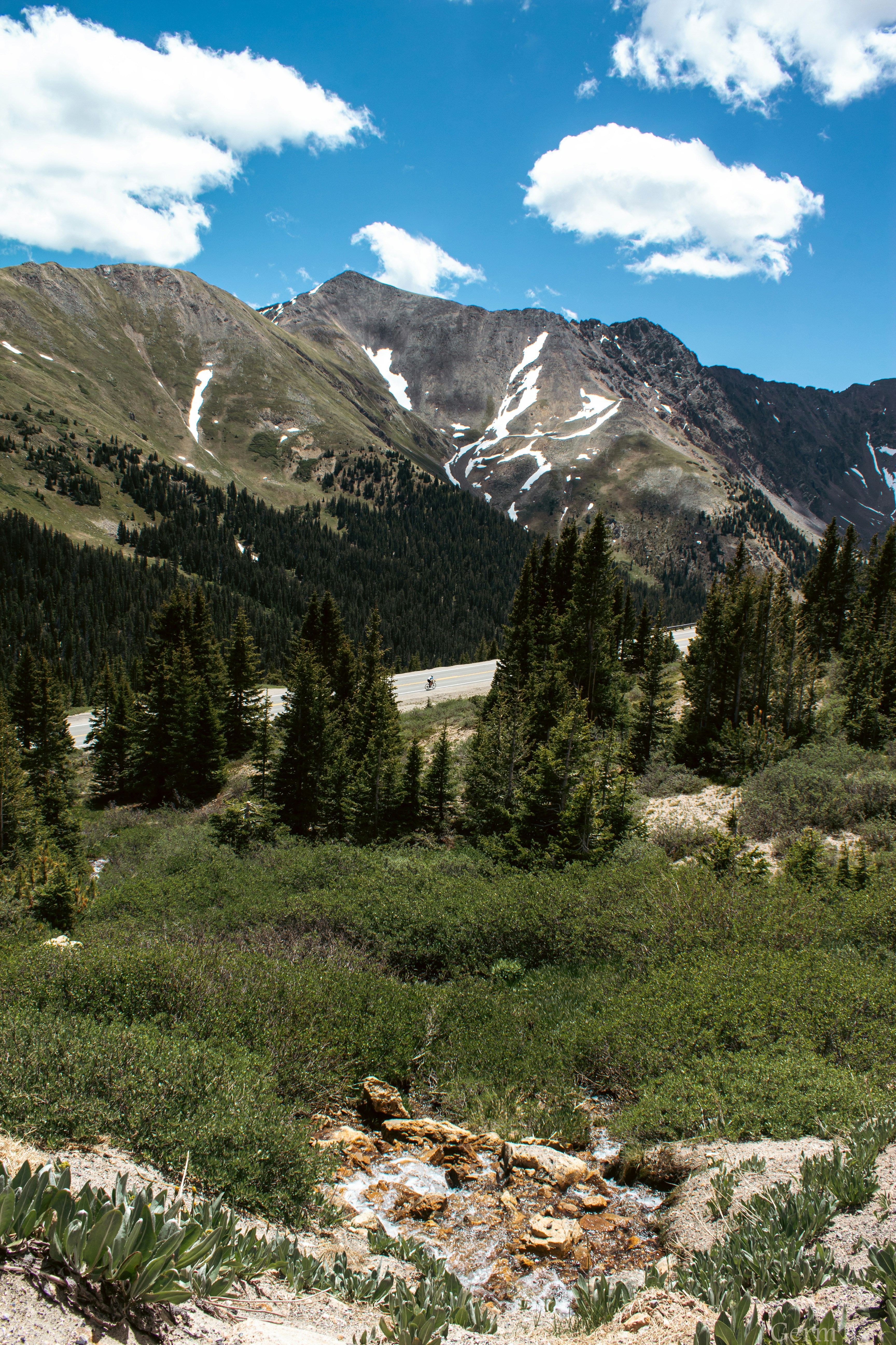 a view of a mountain range with a creek in the foreground