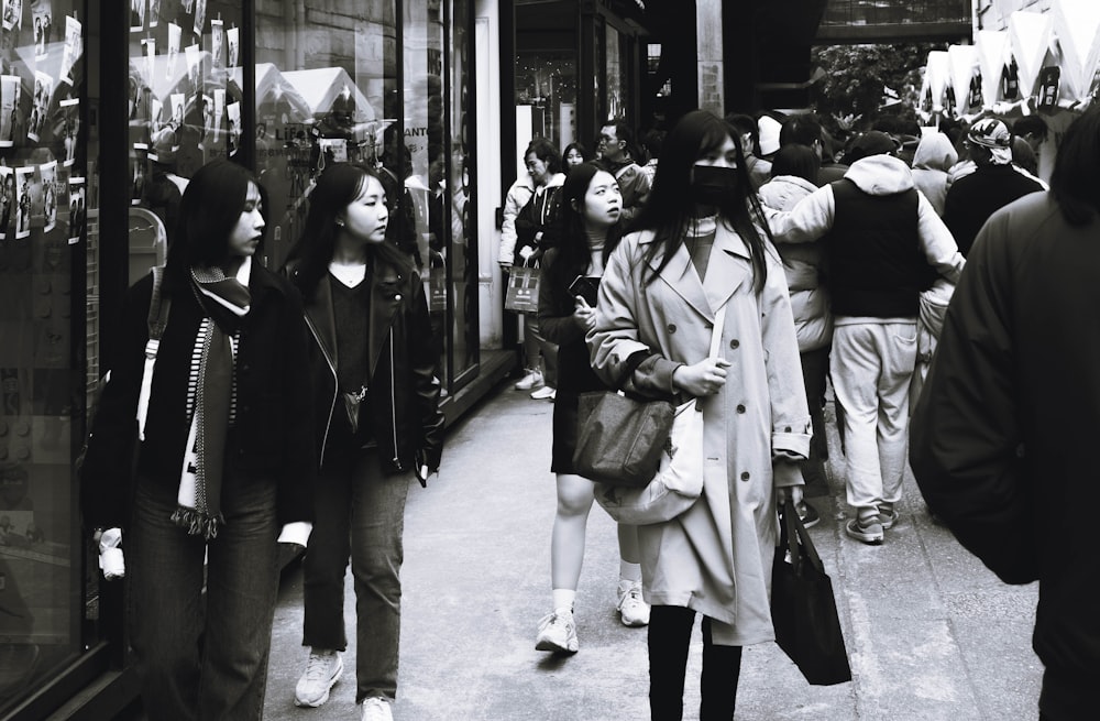 a group of people walking down a street next to tall buildings