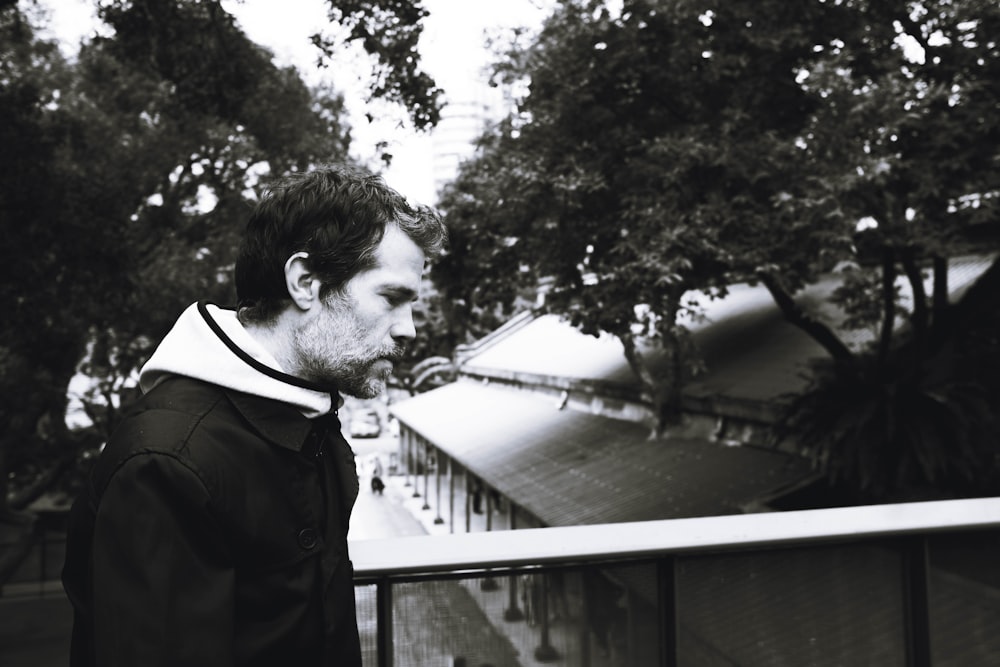 a man standing on top of a balcony next to a tree