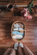 Close-up of soft, cozy slippers resting on a warm wooden floor beside a steaming cup of tea.