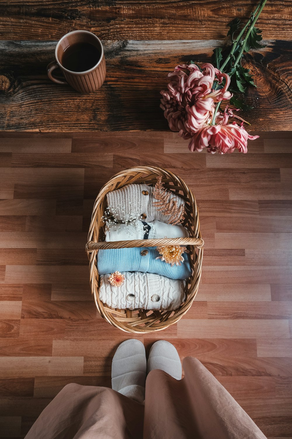 a person standing on a wooden floor next to a basket of clothes
