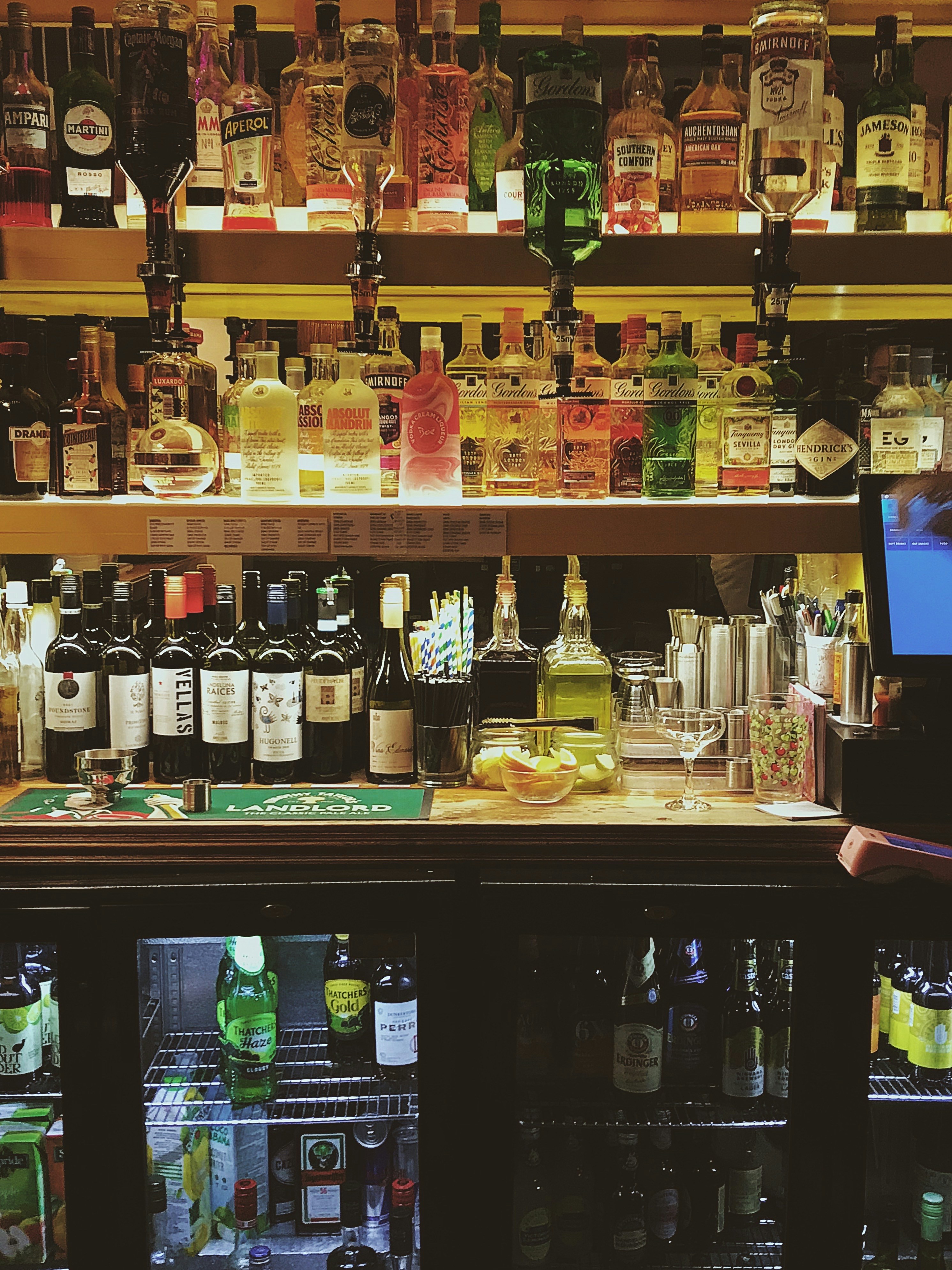 a man standing in front of a bar filled with bottles of alcohol