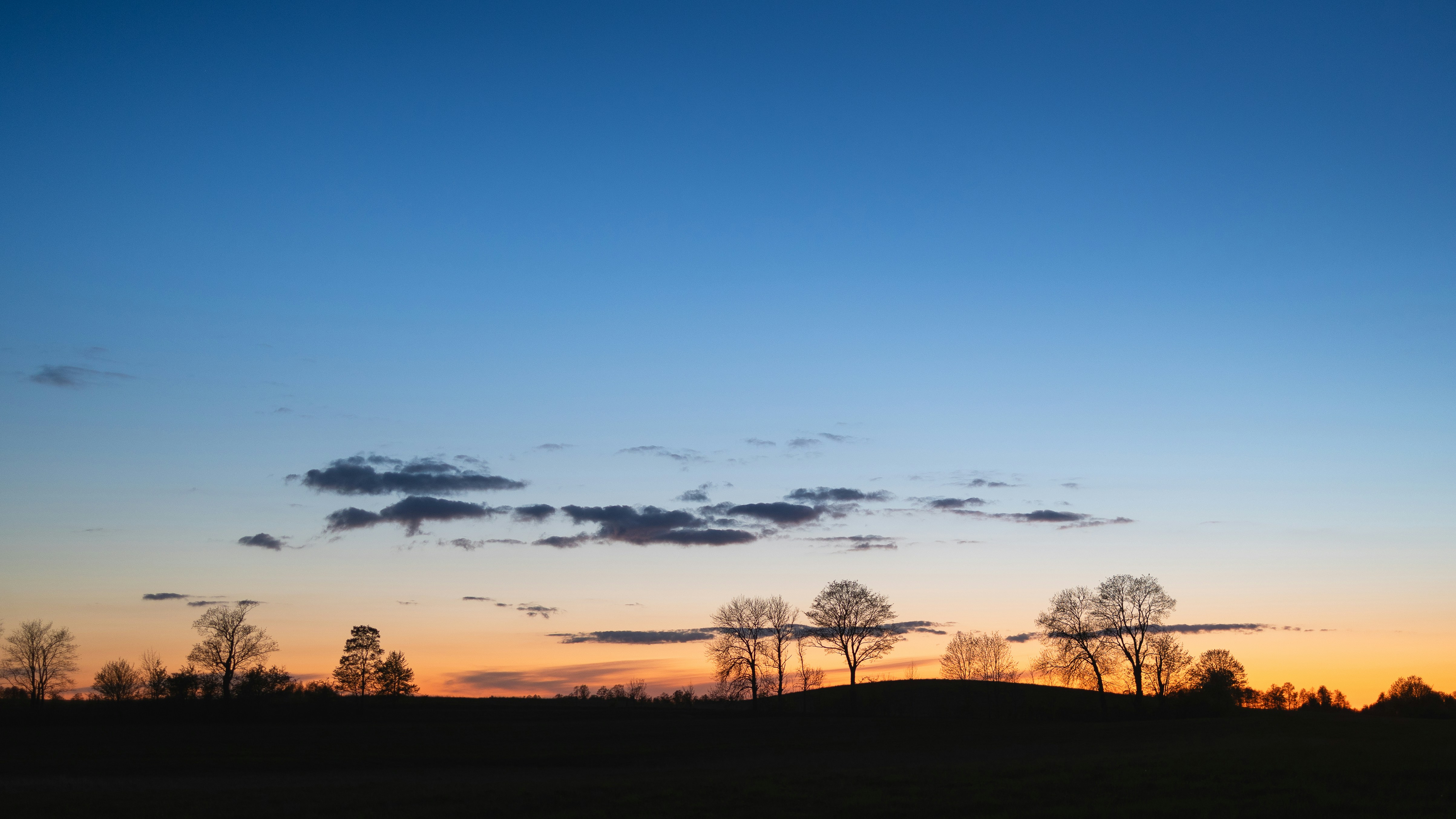 the sun is setting over a field with trees
