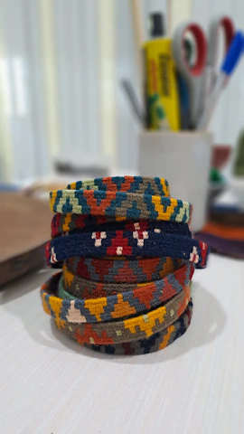 A stack of colorful gemstone bracelets catching the light on a rustic wooden table.