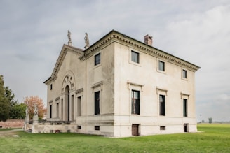 a large white building sitting on top of a lush green field