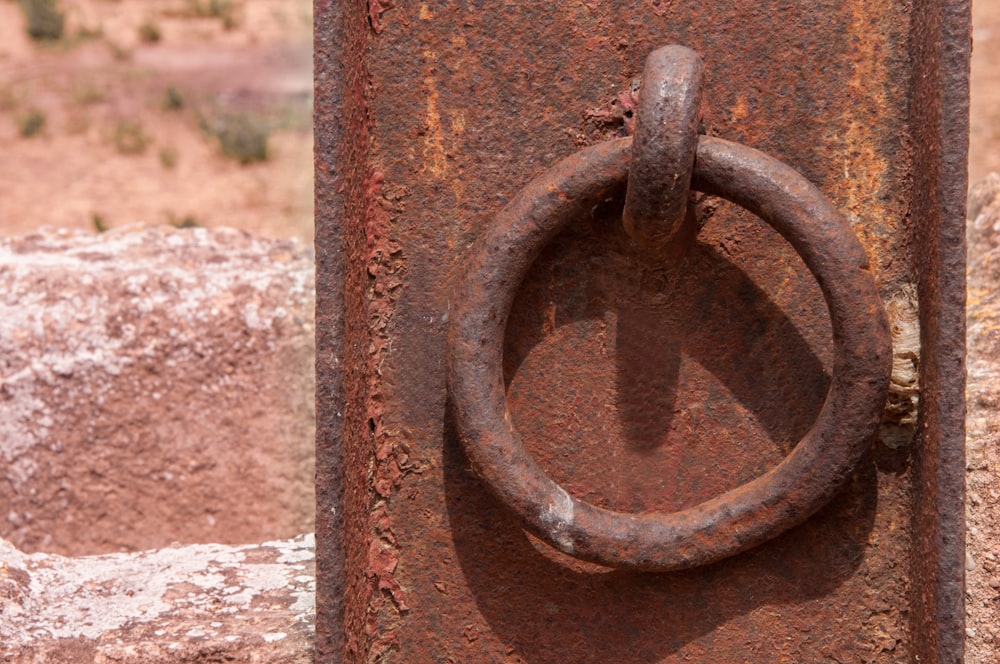 a rusted metal door with a ring on it