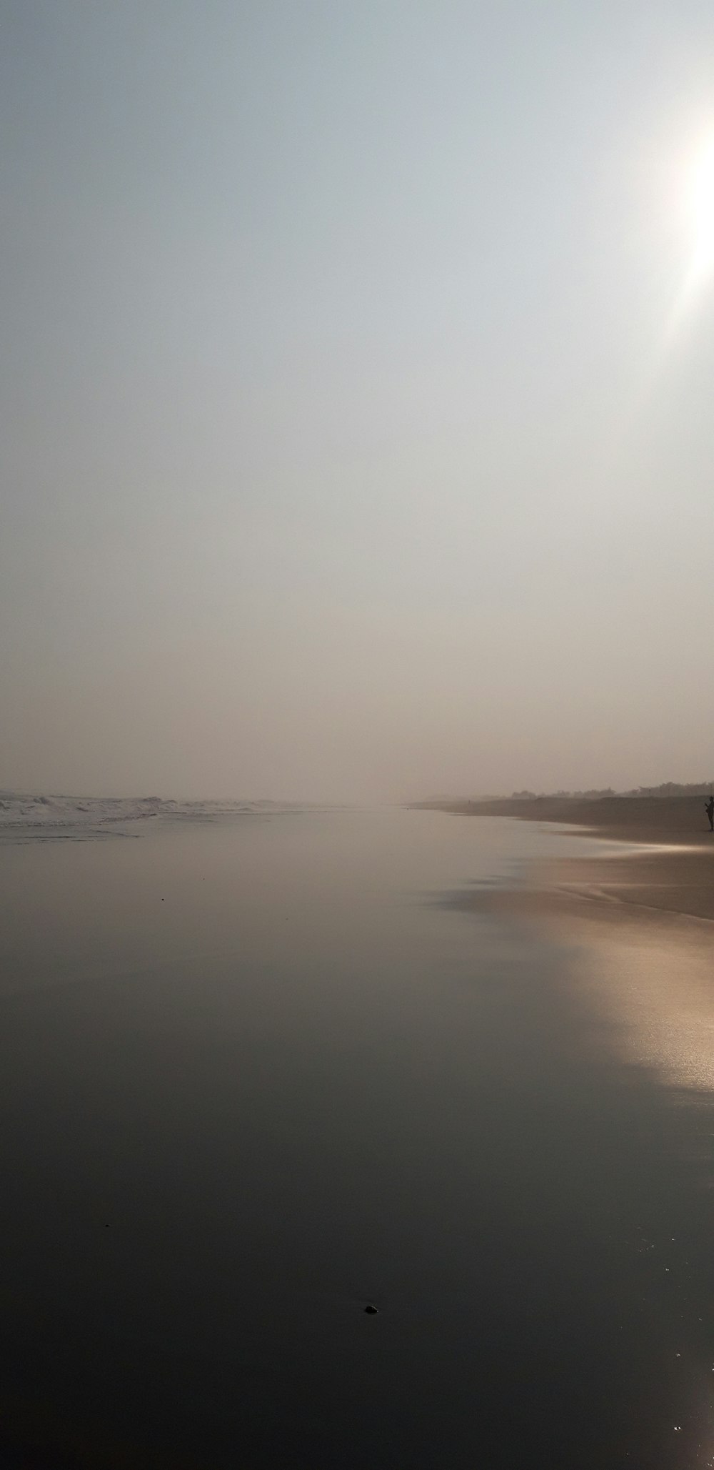 the sun is shining over the water on the beach