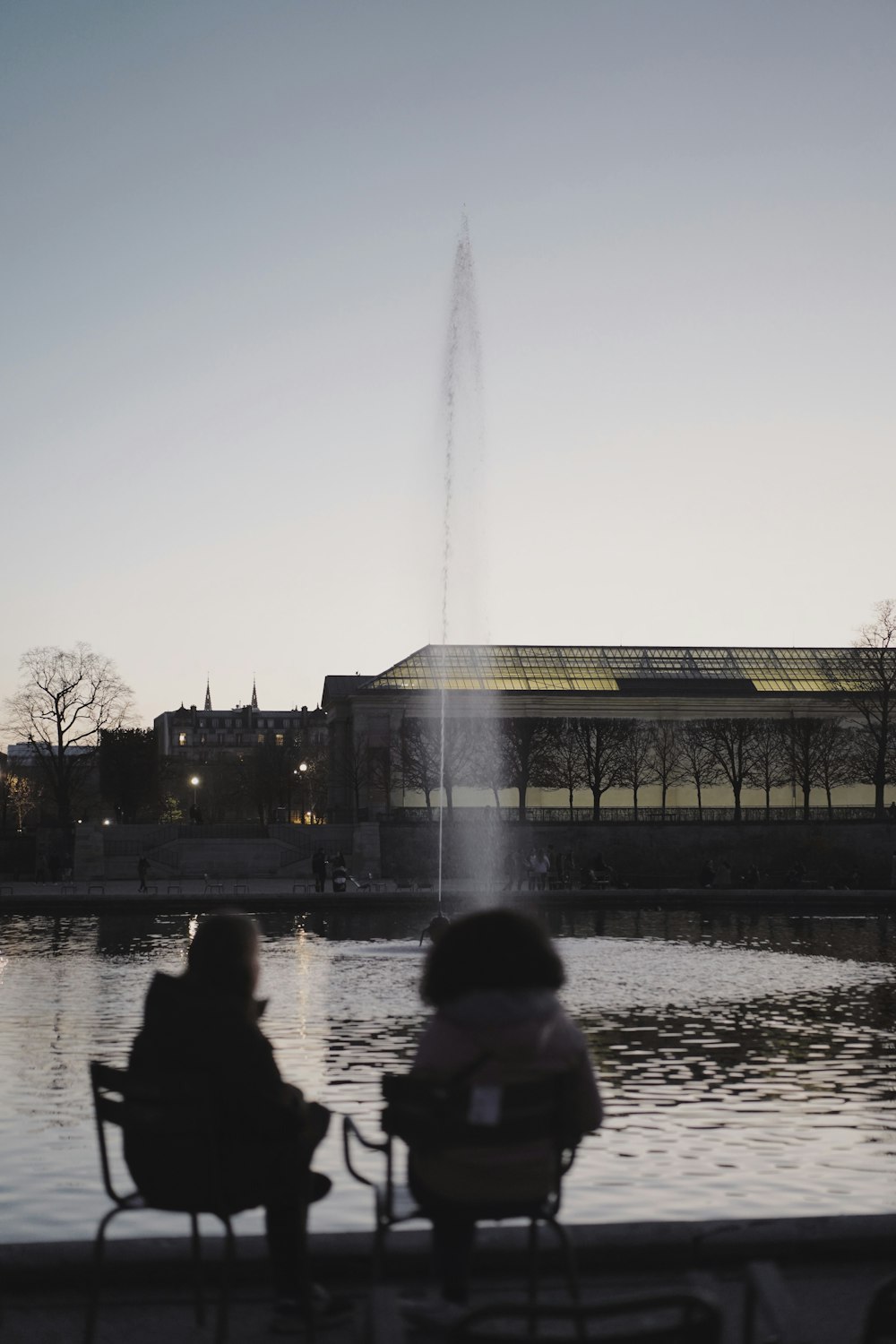 two people sitting in chairs near a fountain