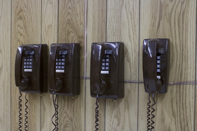 three old fashioned telephones on a wooden wall