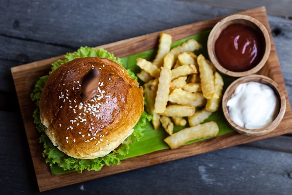 a hamburger and french fries on a wooden tray
