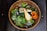A vibrant salad bowl filled with fresh vegetables and grains on a wooden table.