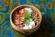 A bowl of organic malt surrounded by fresh ingredients on a kitchen counter.