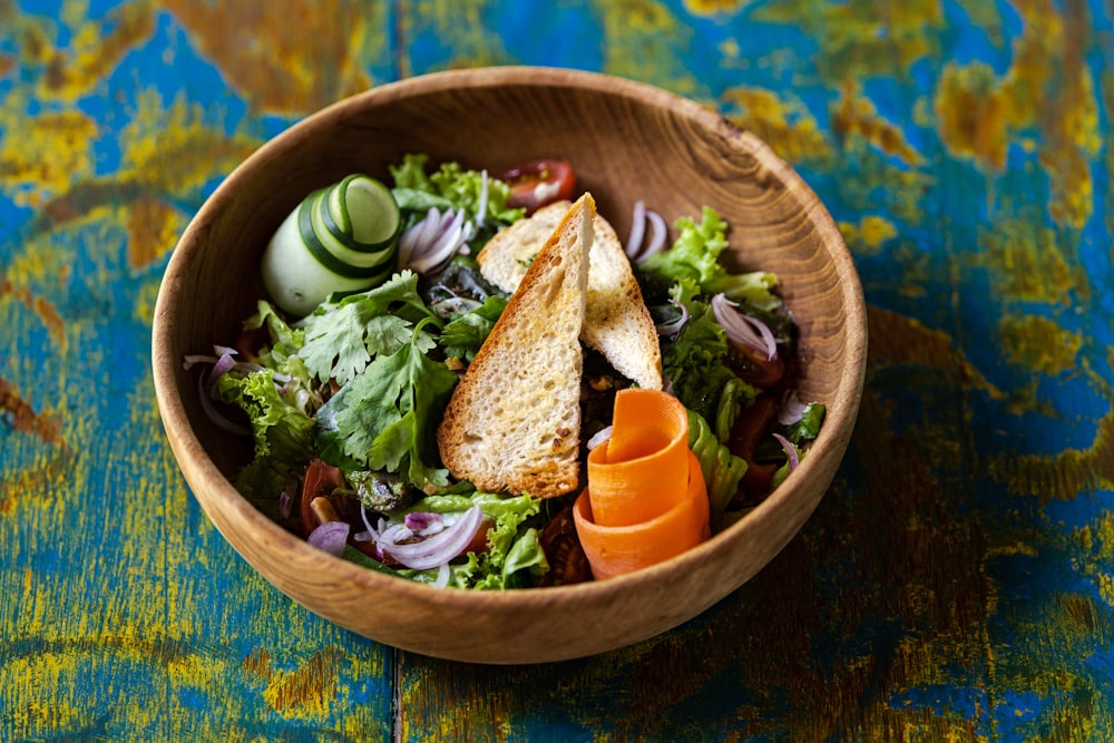 a wooden bowl filled with salad and vegetables