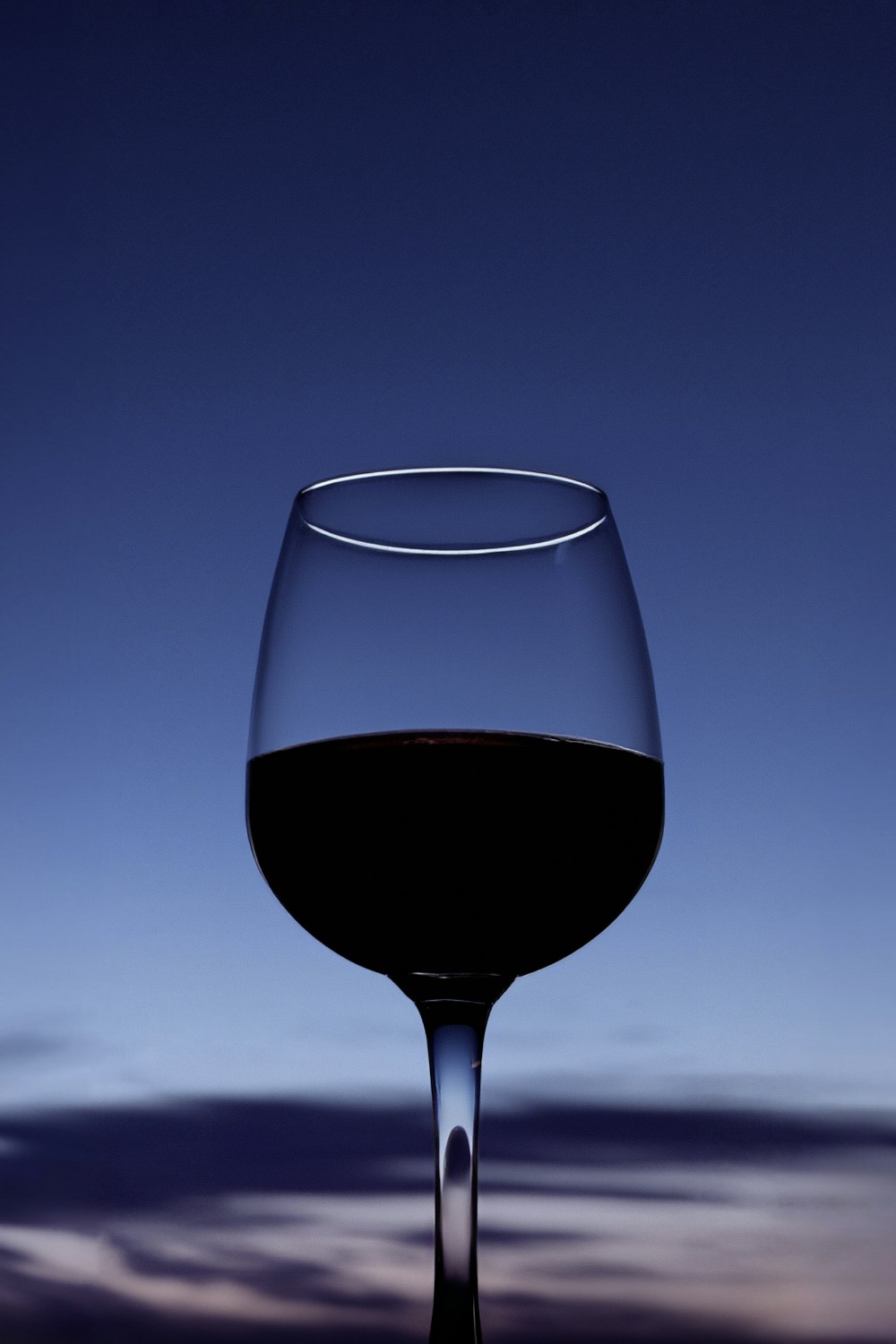 a close up of a wine glass with a sky in the background