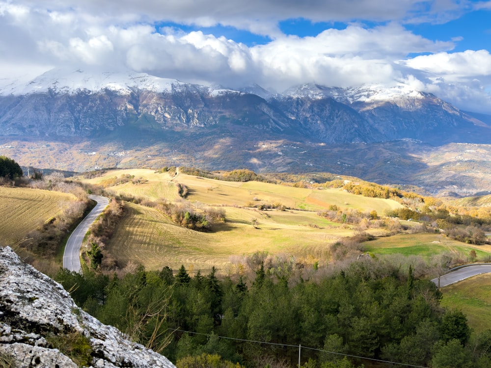 a scenic view of a mountain range with a winding road in the foreground