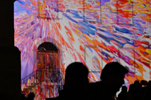 A nighttime outdoor building facade illuminated with colorful videomapping projections.