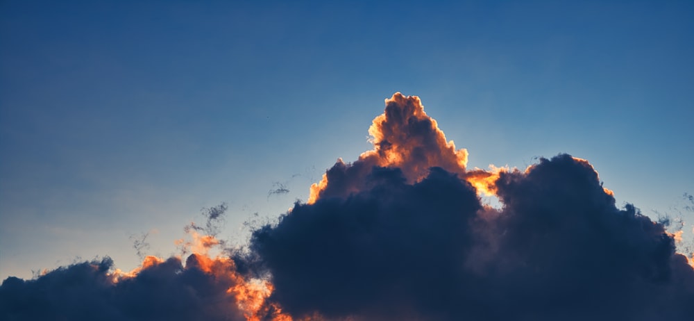 a large cloud in the sky with the sun behind it