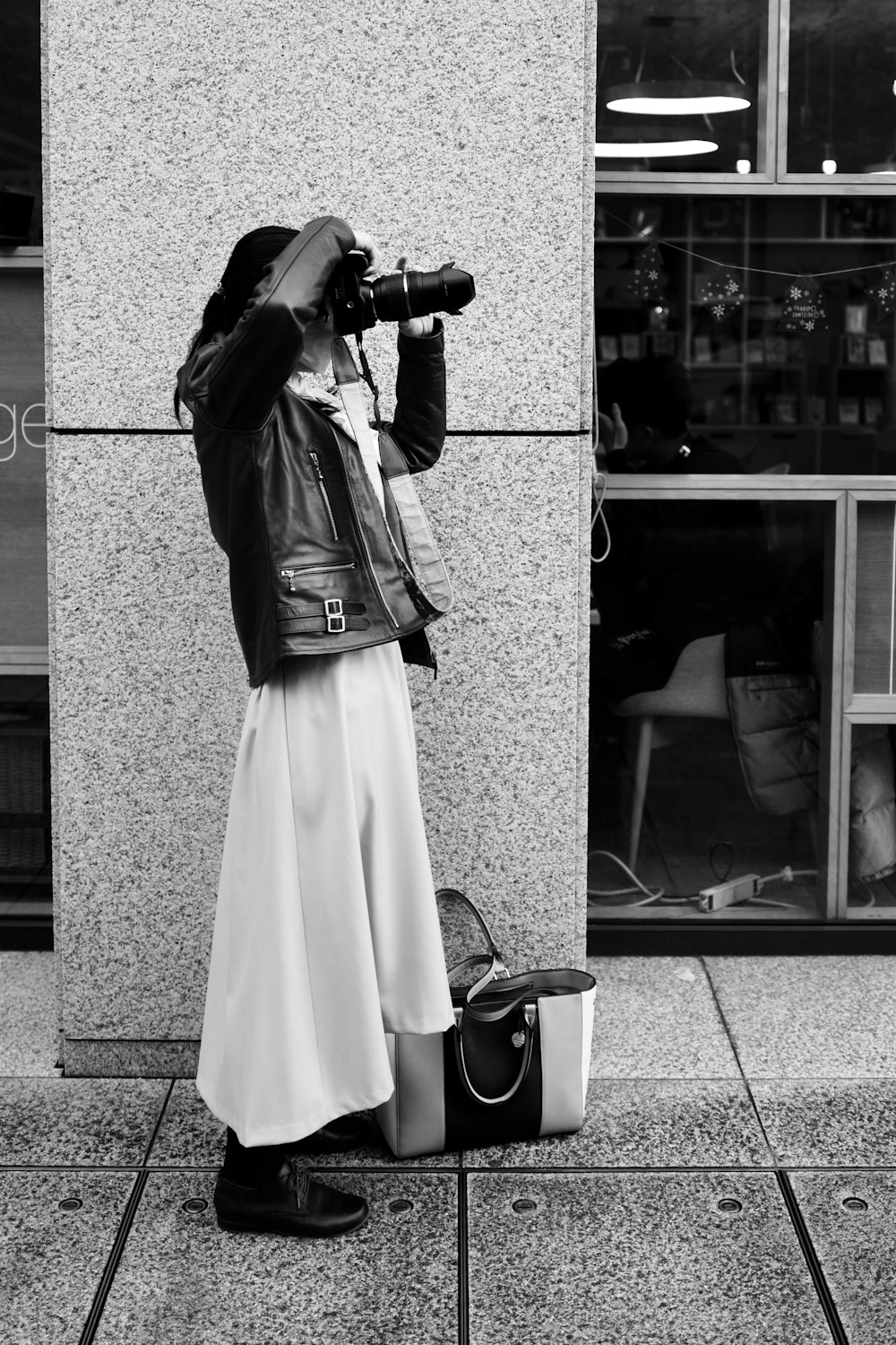 a woman standing on a sidewalk taking a picture with a camera