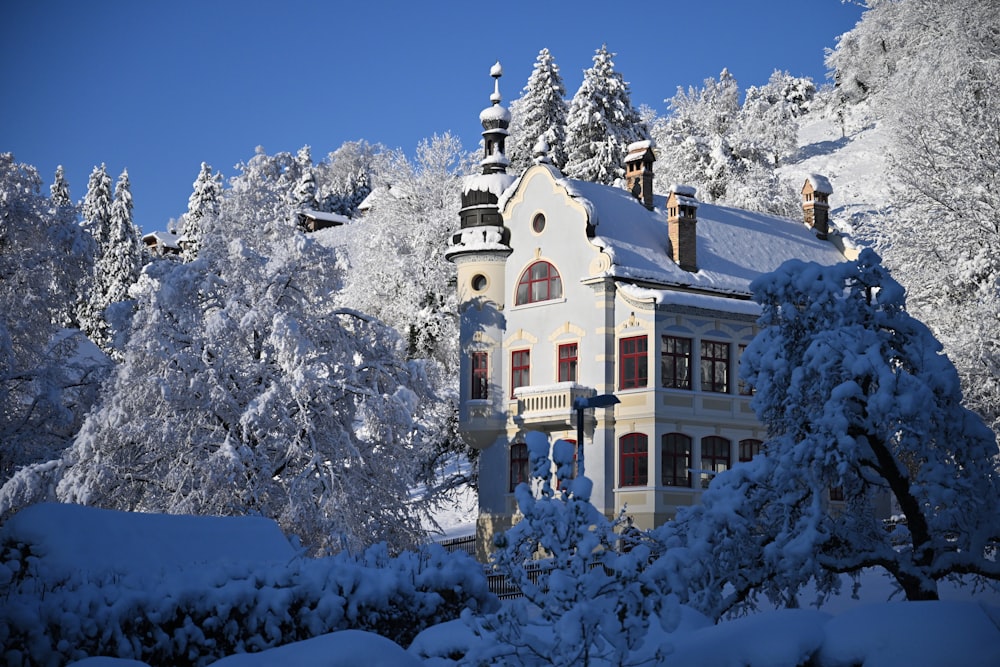 a large white house surrounded by snow covered trees