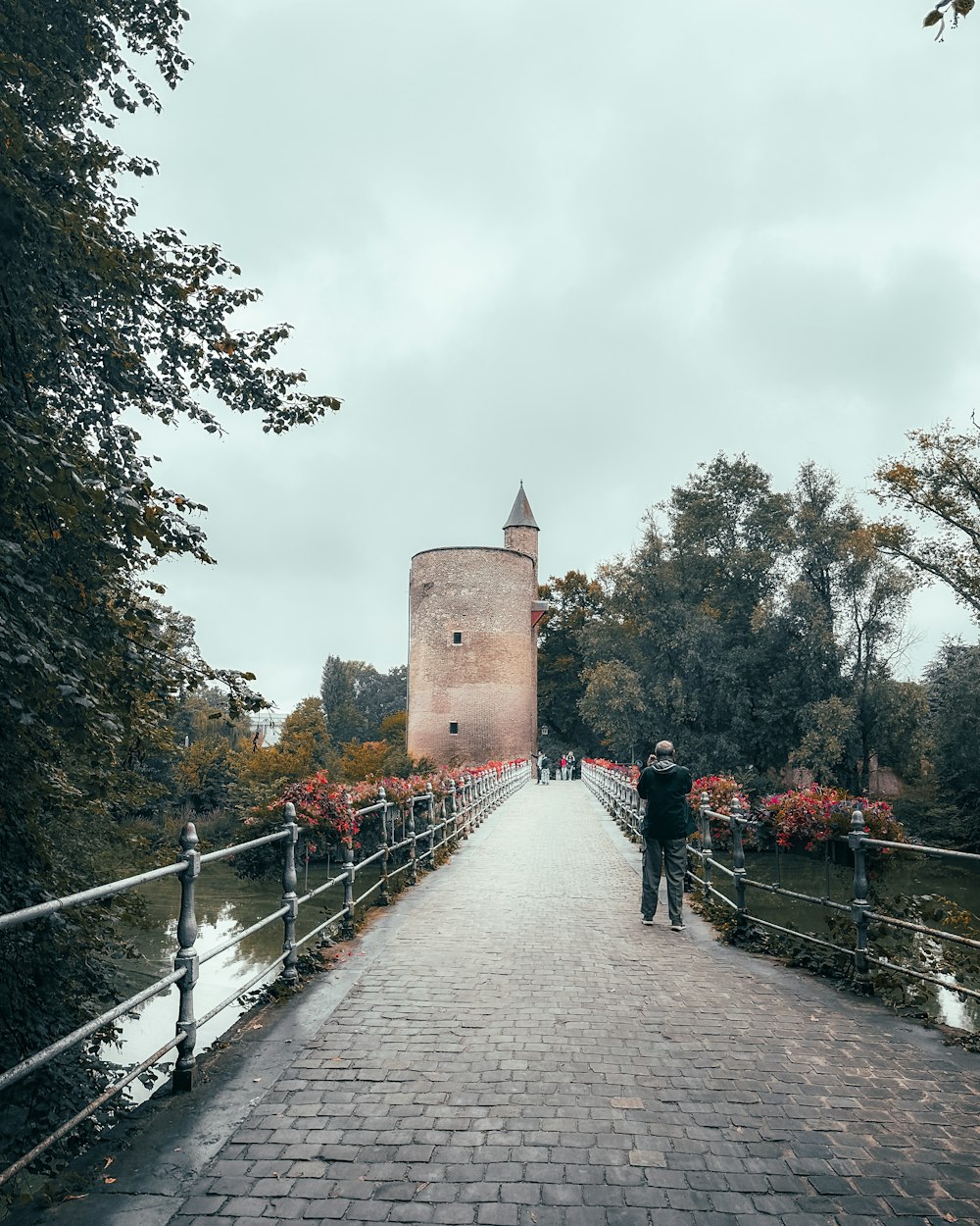 a man walking across a bridge over a river