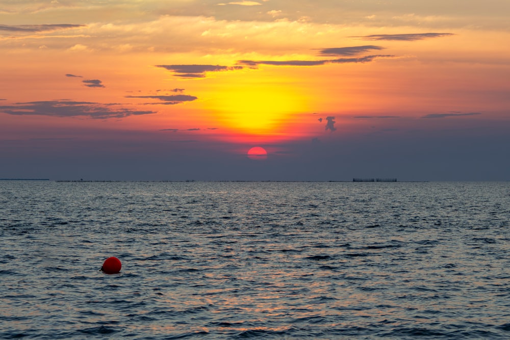 ein großes Gewässer mit einem Sonnenuntergang im Hintergrund