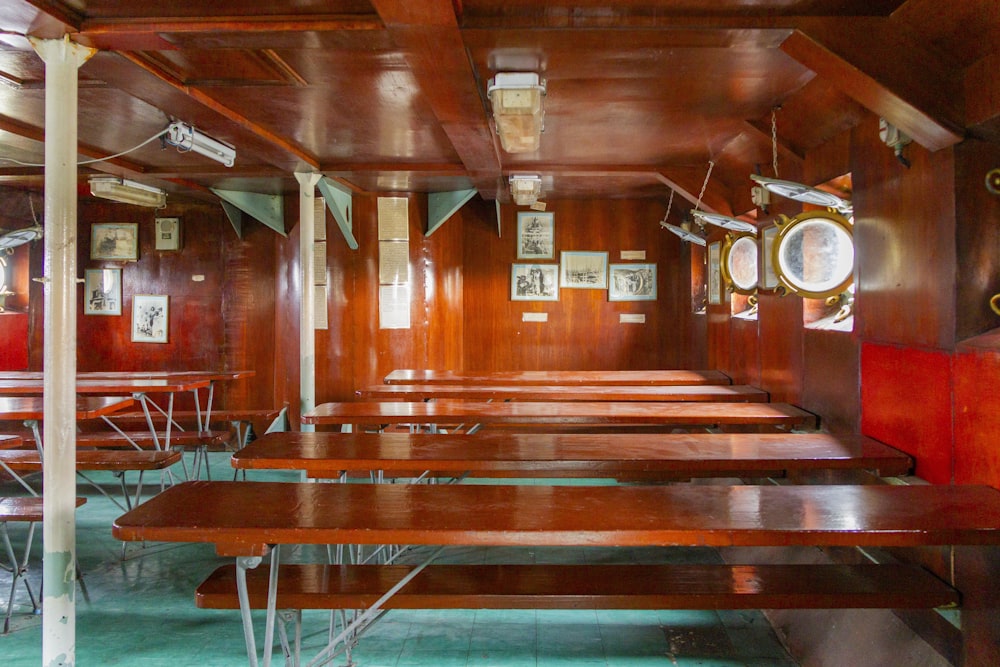 a row of wooden tables sitting inside of a room