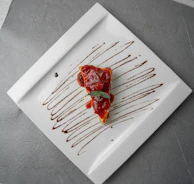 Rich chocolate cake slice topped with berries and a drizzle of chocolate sauce on a dark slate.