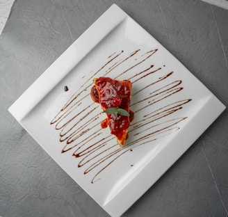 Close-up of a chocolate cake slice topped with berries and a drizzle of caramel sauce on a white plate.