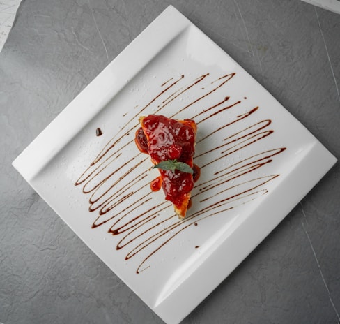 Close-up of a chocolate cake slice topped with berries and a drizzle of caramel sauce on a white plate.