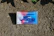 An audio cassette tape with a cover art featuring a retro-style boombox design placed on a textured, earthy ground. The cover art is vivid with a mix of blue, red, and white colors, accentuating the boombox imagery.