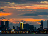 A vibrant city skyline glowing at dusk with planes taking off in the background.