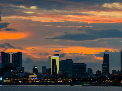 A vibrant city skyline glowing at dusk with planes taking off in the background.
